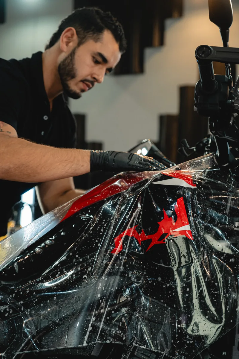 Técnico extendiendo la lámina de PPF sobre el carenado de una moto