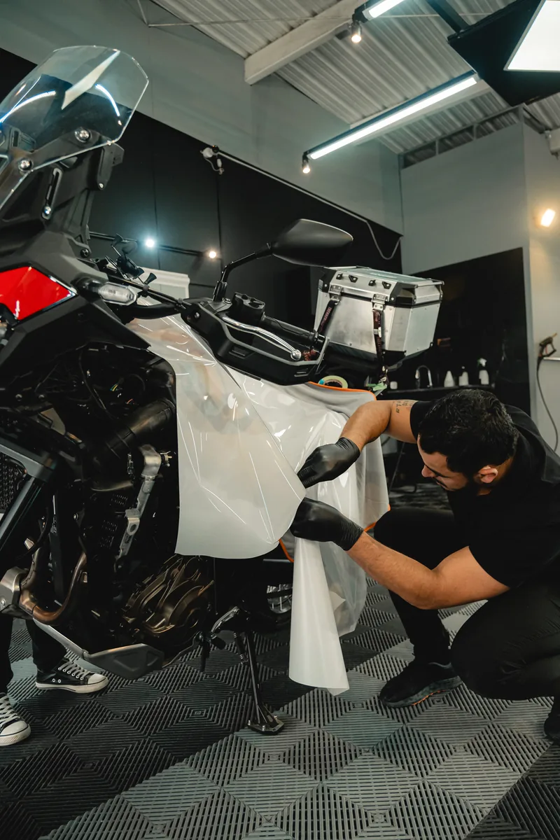 Técnico aplicando película de protección de pintura sobre una motocicleta