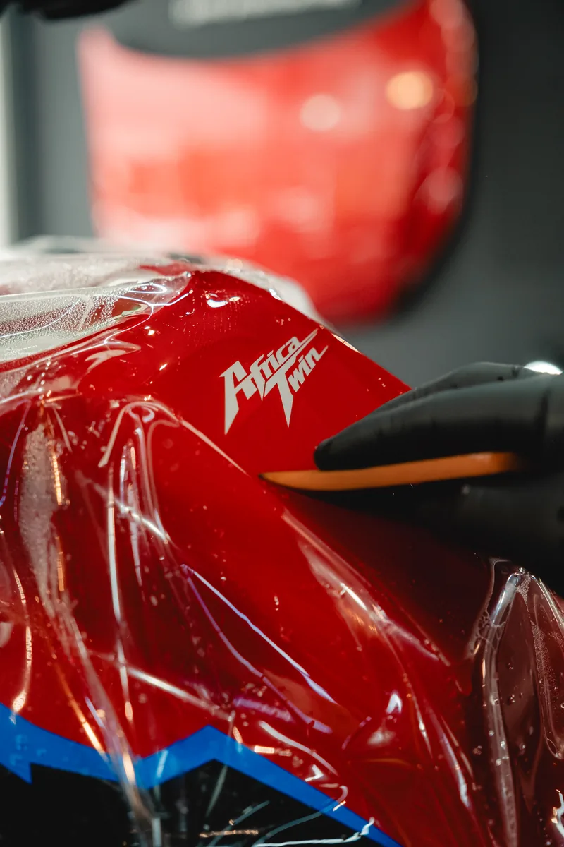Detalle de película de protección aplicada sobre el tanque rojo de una moto