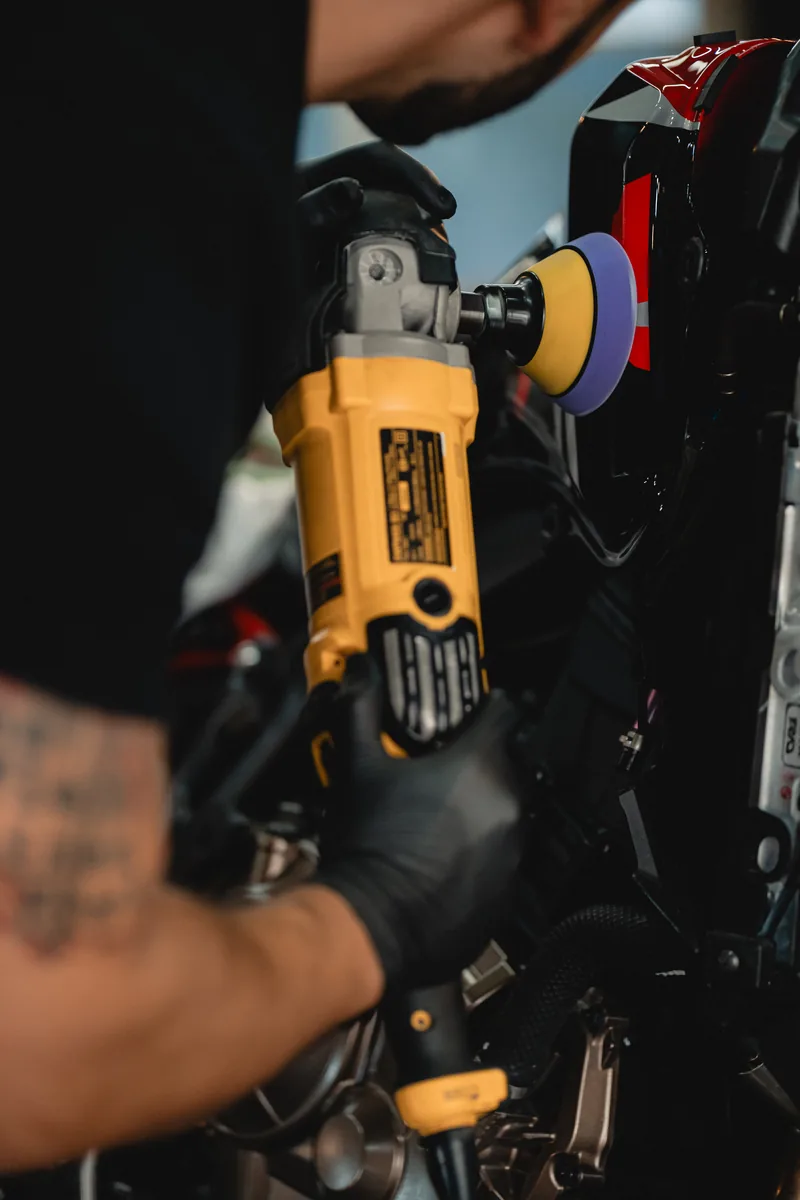 Corrección de pintura con máquina rotoorbital sobre carenado rojo