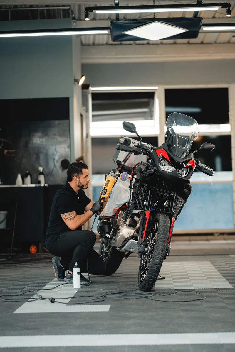 Técnico agachado trabajando sobre una motocicleta BMW GS en el taller, vista general.